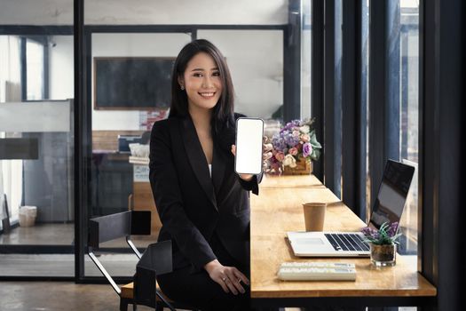 Asian woman showing smartphone with blank screen at cafe. Blank screen for your advertising.