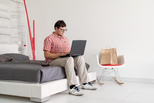 Online shopping concept. Young man sitting on the bed and shopping online using tablet looking at the credit card, copy space