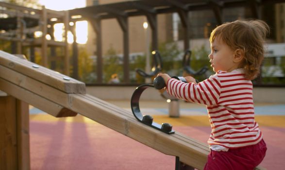 Little girl on the playground in the park. Good sunny day