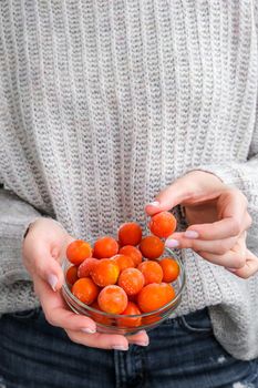 Female hands holding bowl with Frozen Cherry Tomatoes. Vegetable preservation. Harvest. Veganism, vegetarian healthy eating. Fitness diet