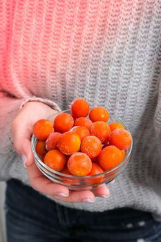 Female hands holding bowl with Frozen Cherry Tomatoes. Vegetable preservation. Harvest. Veganism, vegetarian healthy eating. Fitness diet