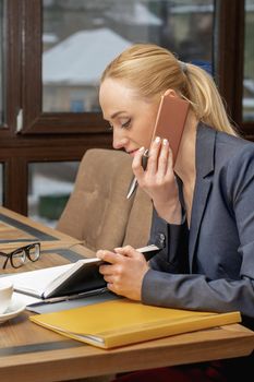 Business Woman in black suit is talking by mobile phone in home office.