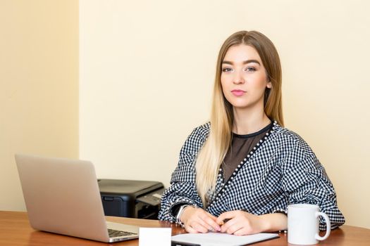 Portrait of a casual business woman sitting at her workplace in home office.