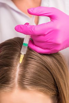 Close up of doctor cosmetologist making mesotherapy injections in head of woman. Concept of mesotherapy.