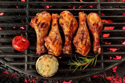 Chicken pieces on a cast iron grill, delicious meat cooked on wooden charcoals