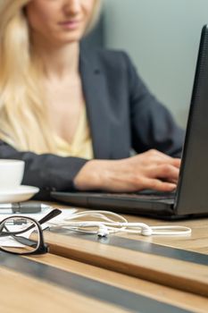 Eyeglass with coffee on office table on female business worker background.