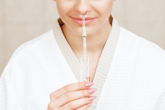 Woman receives nasal inhalation Maholda by essential oil in nose at spa.