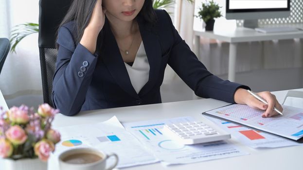 Cropped shot of stressed business woman checking financial document at her workplace.