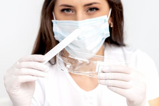 woman wearing white protective mask holding wooden manicure stick