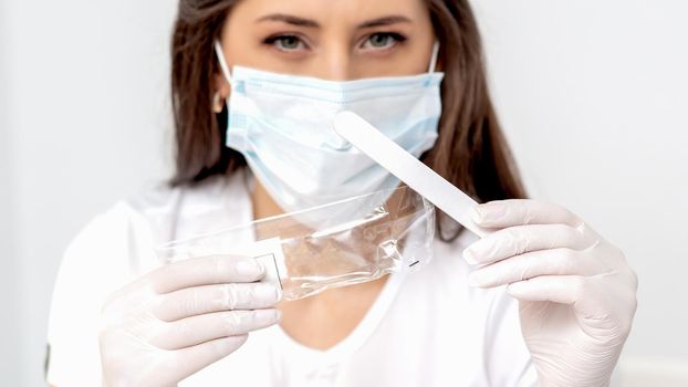 Woman holding medical tool wearing mask in salon.