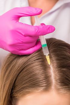 Close up of doctor cosmetologist making mesotherapy injections in head of woman. Concept of mesotherapy.