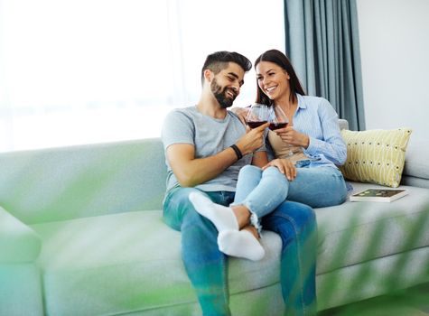 Portrait of a lovely young couple drinking wine together on sofa at home