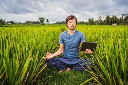 Handsome man learns to do yoga, watch educational video on tablet.