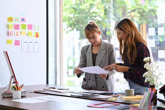 Two young women designer brainstorming and working on mobile app interface wireframe design together.