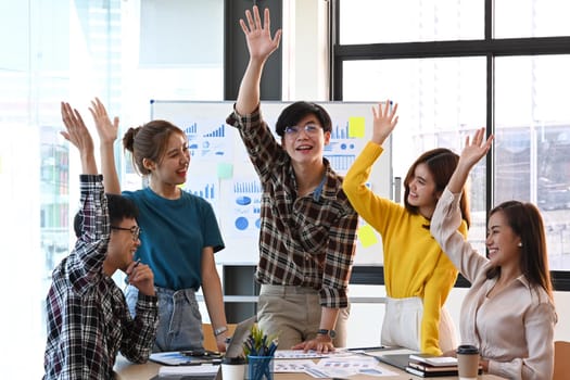 Overjoyed young diverse employees celebrating business success or victory together in office.