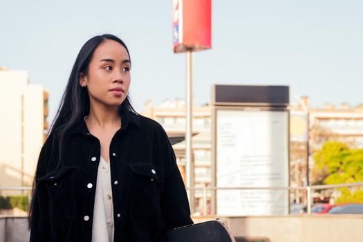 young asian woman waits at subway station exit, concept of urban lifestyle