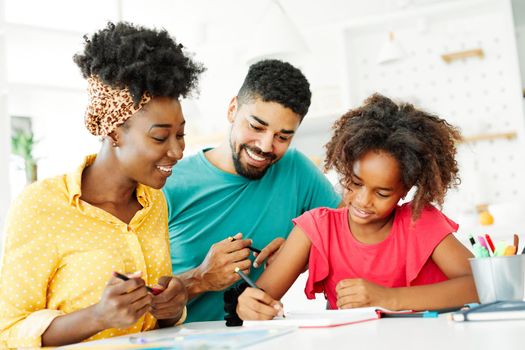 father and mother teaching daughter and helping with homework at home