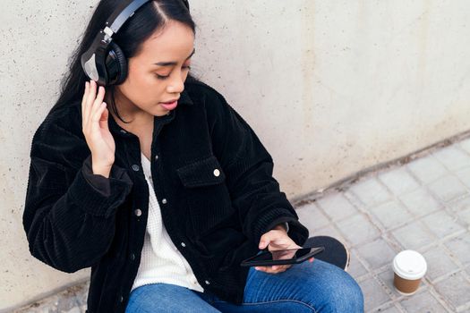 young asian woman with headphones enjoys listening to music with her mobile phone