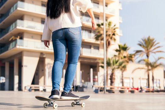 unrecognizable woman riding a skateboard at city street