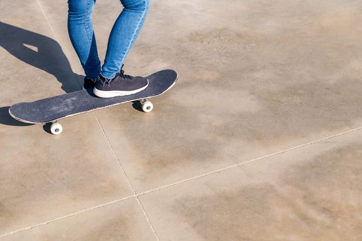 skateboard and feet of an unrecognizable person on a concrete floor
