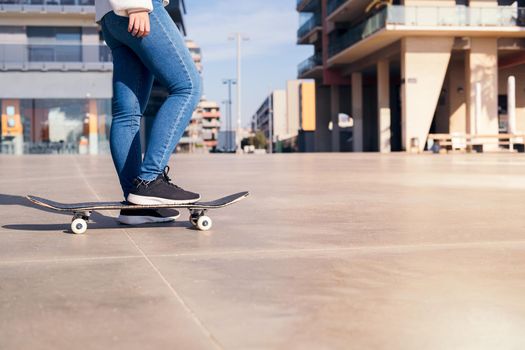 skateboard and legs of an unrecognizable person on a concrete floor at city