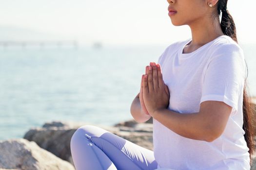detail of the hands of an unrecognizable woman meditating sitting by the sea, concept of spirituality and relax
