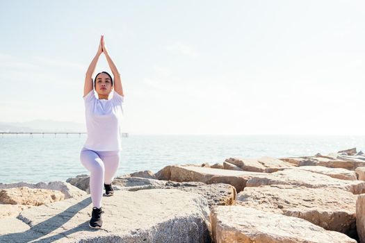 young asian woman practicing yoga by the sea, concept of spirituality and relax