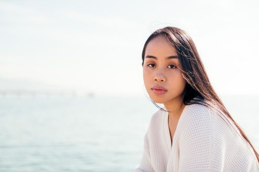 young asian woman dressed in white looking at camera with serious and relaxed expression, concept of beauty and purity