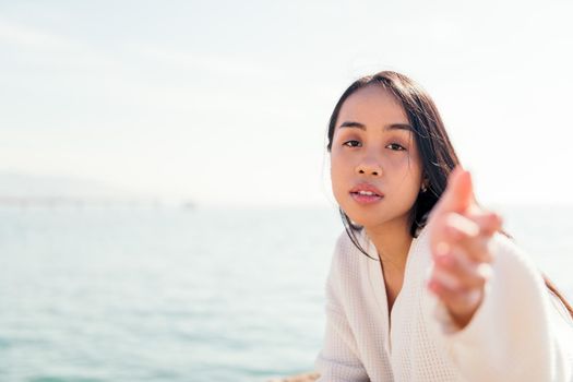 young asian woman dressed in white reaching out her hand to the camera, concept of beauty and purity