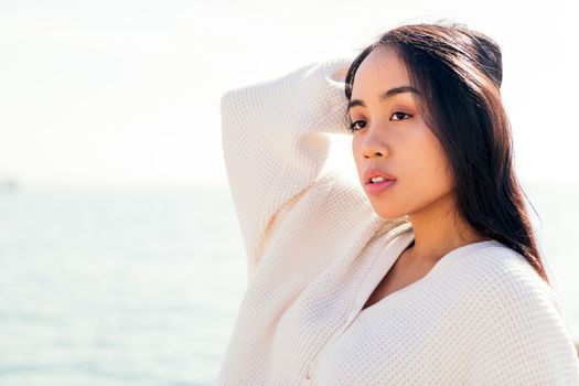 serious young asian woman in white touching her hair, concept of beauty and purity