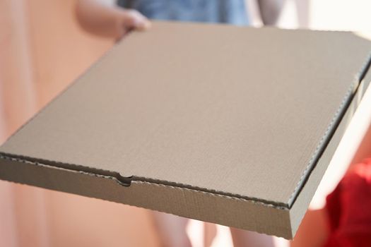 a square cardboard pizza box in the hands of a girl.