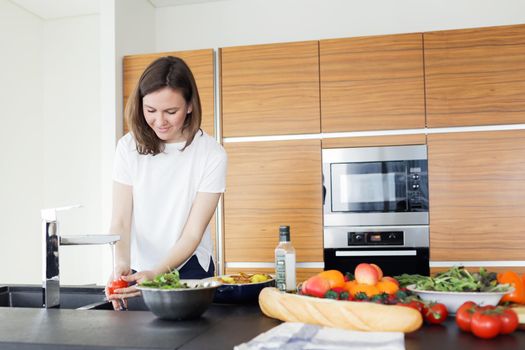 Young woman cooking healthy food in the kitchen. Young woman washing tomatoes in the kitchen