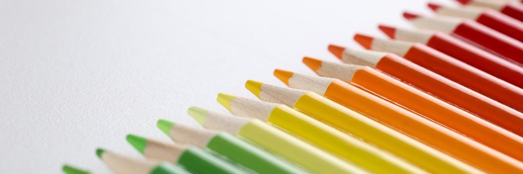 Bright colored pencils with sharp tips lie in a row, close-up. Collection of wooden green red and yellow pencils, learning to draw