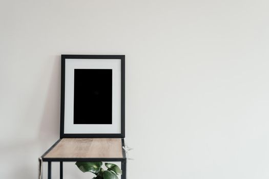 Blank wooden photo frame stands in the interior on a white background. Mockup poster frame close up in home interior.