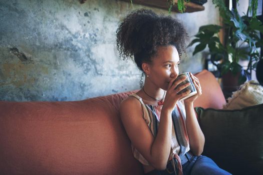 Shot of a beautiful African young woman enjoying a cup of coffee - Stock Photo