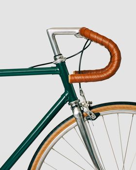 Vintage classic bicycle, forest green paint, with leather tape and saddle. Elegant light grey background. High quality photo