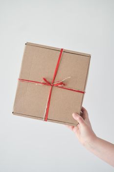 Selected focus. Girl holding a gift box with a red ribbon in her hands. The girl received a gift