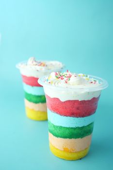 rainbow color cake in a plastic container on table ,