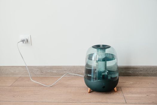 Modern air humidifier on a white wall background. Humidifier spreading steam into the living room.