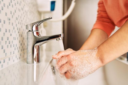 The young girl washes her hands with soap to prevent coronavirus. Hygiene to stop spreading coronavirus.