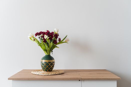 Bouquet of tulips and chrysanthemums in a vase on a white background. High-quality photo