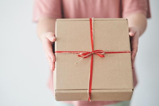 Selected focus. Girl holding a gift box with a red ribbon in her hands. The girl received a gift