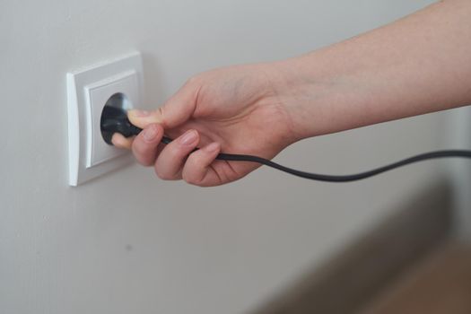 A young girl inserts a plug into an outlet. Young woman plugs the phone charger into the socket. High quality photo