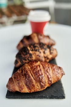 Red cup with coffee and a croissant on a table in a cafe. Morning breakfast. High-quality photo