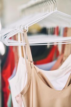 Multi-colored dresses hang on hangers in the store. Sale of women's dresses. Variety of different female colorful clothing hanging.