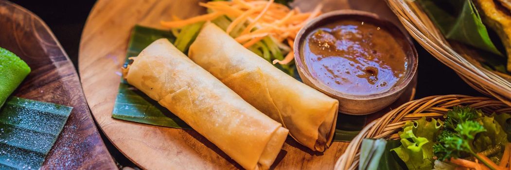 Fried spring rolls served with salad and sauce. Traditional Indonesian and Asian dish. BANNER, LONG FORMAT