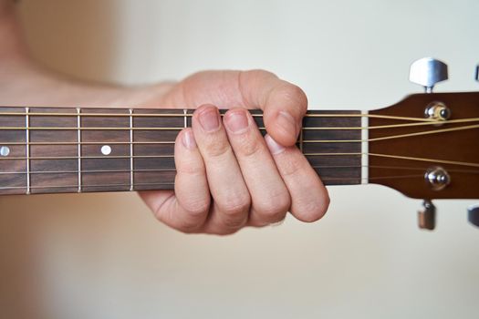 Guitar Player Hand or Musician Hand on Acoustic Guitar String with soft natural light in close up view