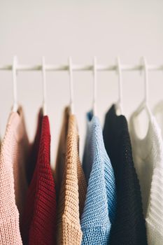 multicolored women's woolen sweaters on hangers. Sale in a fashion store. High quality photo