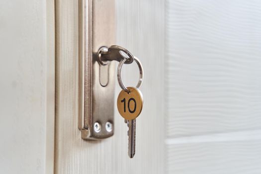 A key with a key fob in the keyhole of the door. Buy a new home concept. Real estate market. High quality photo