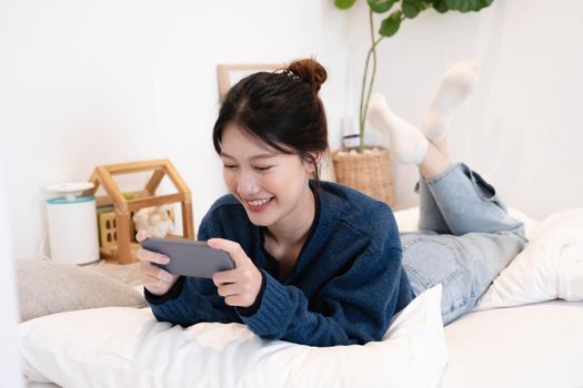 Beautiful woman using a smart phone in the morning on the bed at home.